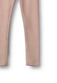 Leggings rose pâle côtelés et doux avec une coupe slim. Présentent un ourlet droit et aucun matériel ou motif visible. Tissu léger.