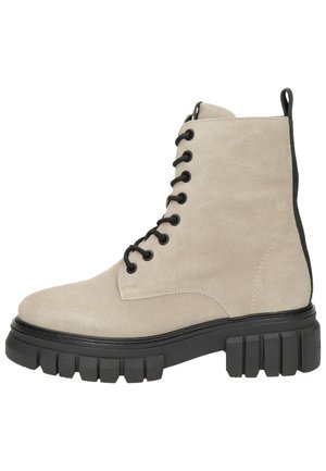 Botte de combat en daim beige avec semelle crantée noire épaisse, lacets noirs et languette noire à l'arrière.