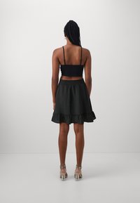 Must have riietega must cropped top, koos musta kihilise volangseelikuga. Selged kontsadega sandaalid rõhutavad komplekti.