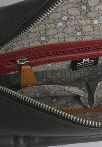 Schwarze Ledertasche mit Reißverschluss, ausgestattet mit einer roten Reißverschlusstasche und einem gemusterten beigen Innenfutter mit braunen und hellblauen Sterndesigns.