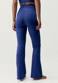 Niebieskie legginsy do jogi o rozszerzanym kroju, z wysokim stanem i gładką fakturą materiału. Posiadają subtelne logo w pobliżu pasa.