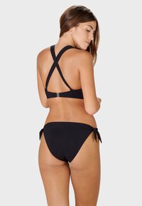 Black bikini set featuring a crisscross back design and adjustable ties on the sides of the bottom. Smooth, stretchy material.