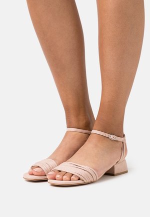 Sandales à talons carrés en cuir lisse, de couleur rose pâle, avec des lanières tissées à l'avant et une bride de cheville munie d'une boucle argentée.