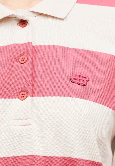 Polo rayé rose et blanc avec une finition texturée, trois boutons roses et un petit logo brodé sur le côté gauche.