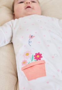 Bílé dětské body s růžovou výšivkou květin a motýlů, s růžovou kapsičkou s designem květináče. Celkově zdobené malými růžovými hvězdičkami.