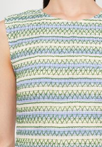 Textilný top s horizontálnymi pruhmi v zelenej, modrej a krémovej farbe s textúrovaným, zberaným dizajnom. Okrúhly výstrih s bezrukávovým strihom.