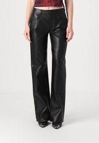 Black leather flared pants with a smooth texture, featuring front pockets and a button closure. Worn with black heeled shoes.