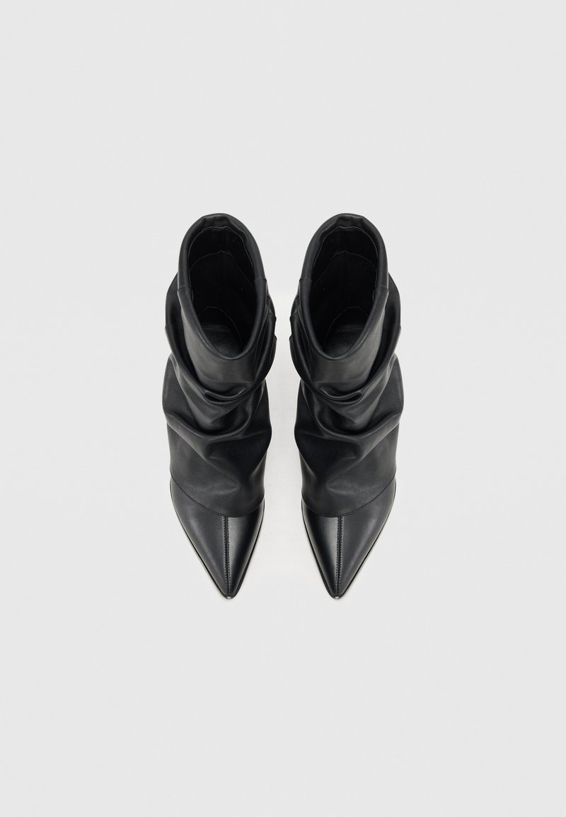 Schwarze Leder-Stiefeletten mit einem lässigen Design, spitzen Zehen und einer glatten Oberfläche, die ein minimalistisches und elegantes Aussehen bieten.