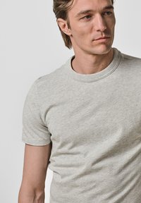 Szara bawełniana koszulka z krótkim rękawem i okrągłym dekoltem, charakteryzująca się miękką teksturą oraz subtelnym wzorem melanżowym.