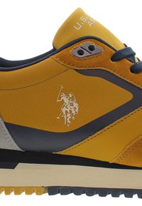 Kellon keltainen ja laivastonsininen lenkkari, jossa on teksturoitu nahka, harmaat korostukset ja kumipohja. Varustettu kohokuvioidulla logolla ja kontrastivärisillä ompeluyksityiskohdilla.