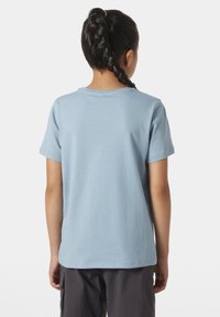 Camiseta de algodón azul claro con mangas cortas, escote redondeado y textura suave. Presenta un diseño simple sin patrones ni acentos.