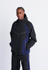 Black and navy hooded jacket with a zip closure, featuring side pockets and a sleek design. The fabric has a smooth texture and modern cut.