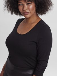 Μαύρη  μπλούζα μακρυμάνικη με στρογγυλή λαιμόκοψη, σε λεία ύφανση και εφαρμοστή σιλουέτα, συνοδευόμενη από μαύρη φούστα ψηλόμεση.