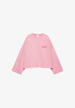 Világos rózsaszín rövidített pulóver széles ujjakkal, és piros "LAID-BACK" felirattal, három csillaggal a bal mellrészen.