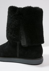 Stivaletto nero alla caviglia in suede con morbida fodera pelosa. Presenta una cerniera laterale e una suola in gomma, che aumentano la durata e il comfort.