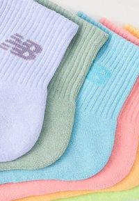 Πέντε πολύχρωμες κάλτσες τοποθετημένες σε στοίβα. Τα χρώματα περιλαμβάνουν λεβάντα, πράσινο, μπλε, ροζ και πορτοκαλί. Ριμπ υφή, με λογότυπο στην κάλτσα λεβάντας.