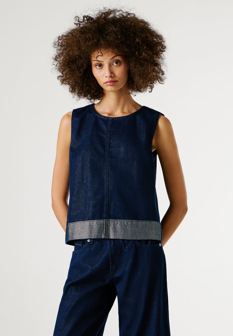 Tume sinine käeauguta topp, valmistatud tekstuurilisest denimist, millel on hõbedane metallist äär. Omab ümardatud kaelust ja lõtvade lõikega disaini.