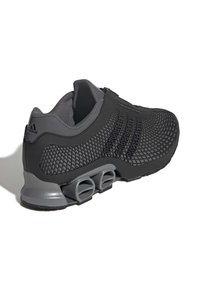 Zapatilla deportiva negra con parte superior de malla, cuello acolchado y una única amortiguación gris en el talón con tres recortes distintos.
