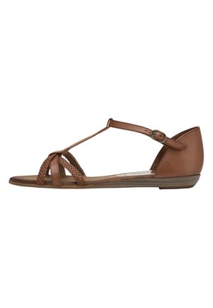 Sandale plate marron avec brides avant tressées, bride de cheville avec boucle et talon fermé, vue de côté sur fond blanc.