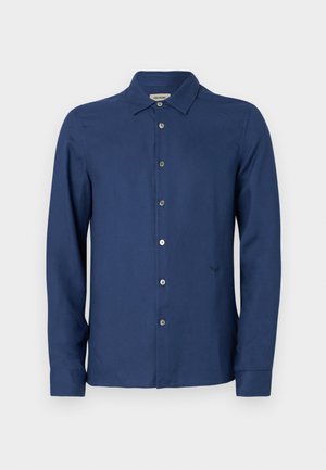 Marineblauwe, langarmige overhemd van een gladde stof; heeft een klassieke kraag, subtiel logo en een standaard knoopsluiting.