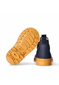 Stivaletti blu navy per bambini con suole in gomma beige, uno che mostra il motivo del battistrada e l'altro visto da dietro.