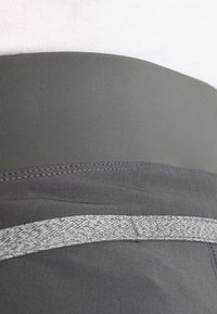 Šedé sportovní šortky s širokým elastickým pasem, hladkým povrchem a melírovým šedým proužkem.