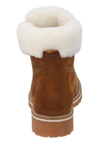Bottine en daim marron avec un col en shearling blanc, présentant un design cousu et une semelle en caoutchouc texturé. Accentuée par un logo sur le côté.