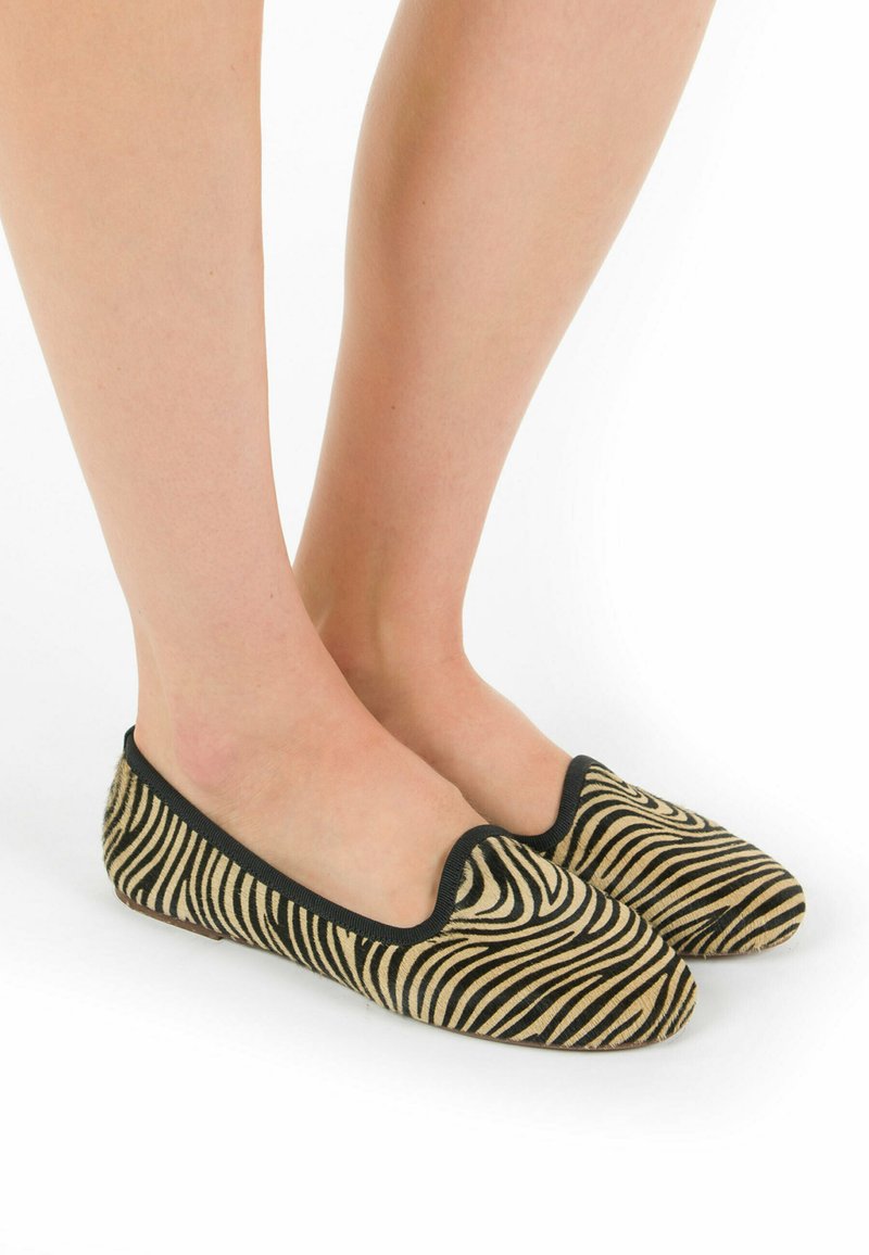 Pantofole piatte con motivo zebra e bordo nero, realizzate in morbido tessuto, dotate di punta arrotondata e suola flessibile per garantire il massimo comfort.