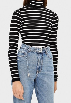 Sort- og hvidstribet ribbet højhalset trøje kombineret med højtaljede lyseblå jeans og et tyndt hvidt bælte.