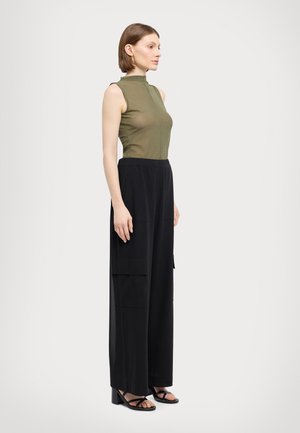 Haut sans manches vert olive avec col montant ; pantalon cargo noir à jambes larges avec poches latérales ; sandales à talons noires. Texture lisse.