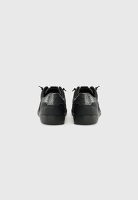 Sneaker nere con retro in finta pelle testurizzata, forma arrotondata, dettagli testurizzati e suola in gomma piatta. Dettaglio di laccatura anteriormente.