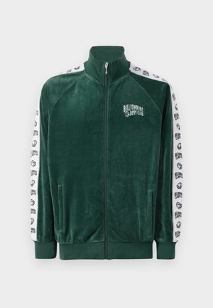 Grøn velour zip-up jakke med høj krave, sidelommer og hvide mønstrede ærmer med "Billionaire Boys Club" logo og detaljer.