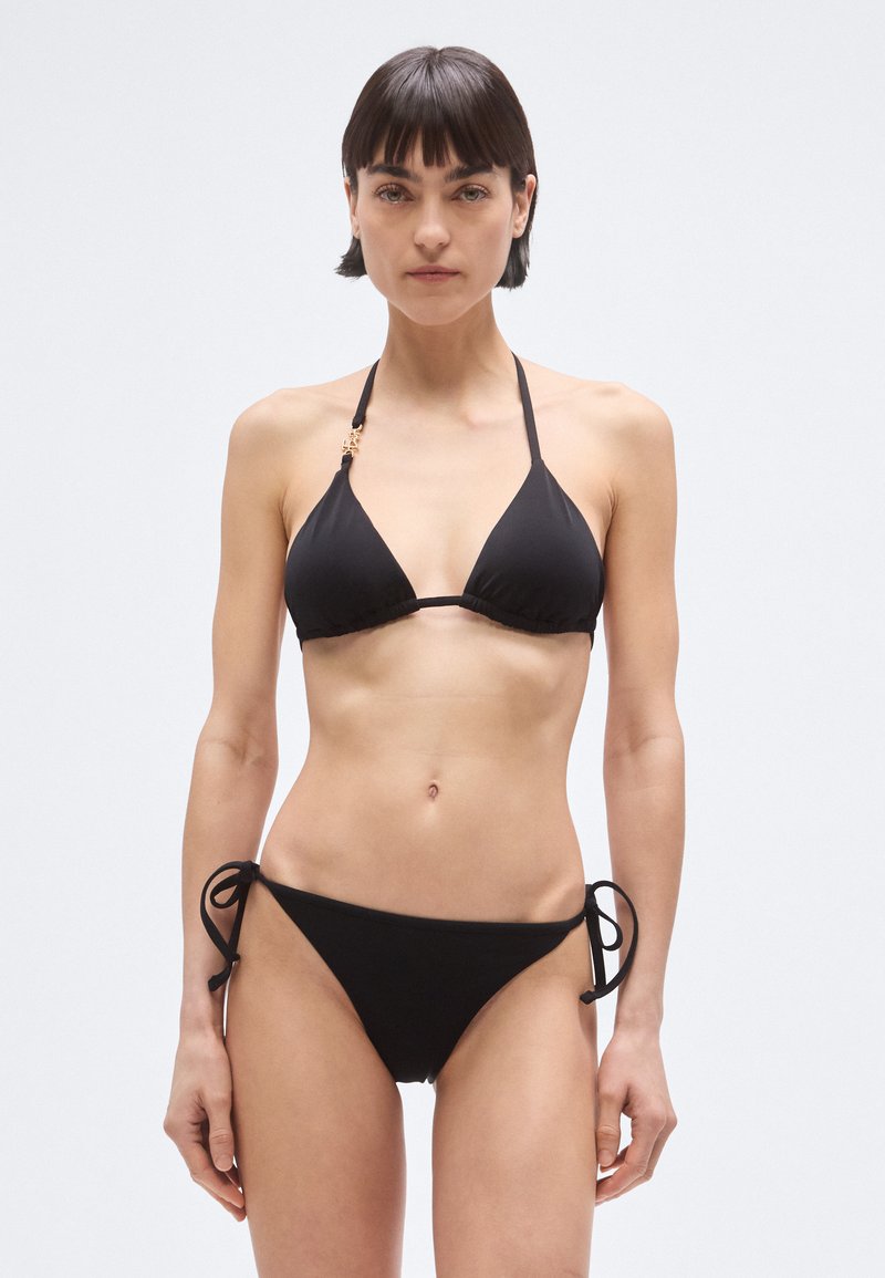 Črni bikini z zgornjim delom v obliki trikotnika s halter naramnicami in spodnjim delom z izrezom v obliki trikotnika. Zavezuje se ob straneh, na zgornjem delu pa je majhen zlat detajl.