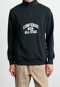Donkergroene pullover sweatshirt met een ritskraag, voorzien van een witte "Converse All Star" graphic en geribbelde manchetten en zoom.