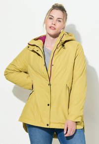 Gul vattentät jacka med huva och rosa foder, med tryckknappar, sidofickor och en något utsvängd nederdel.