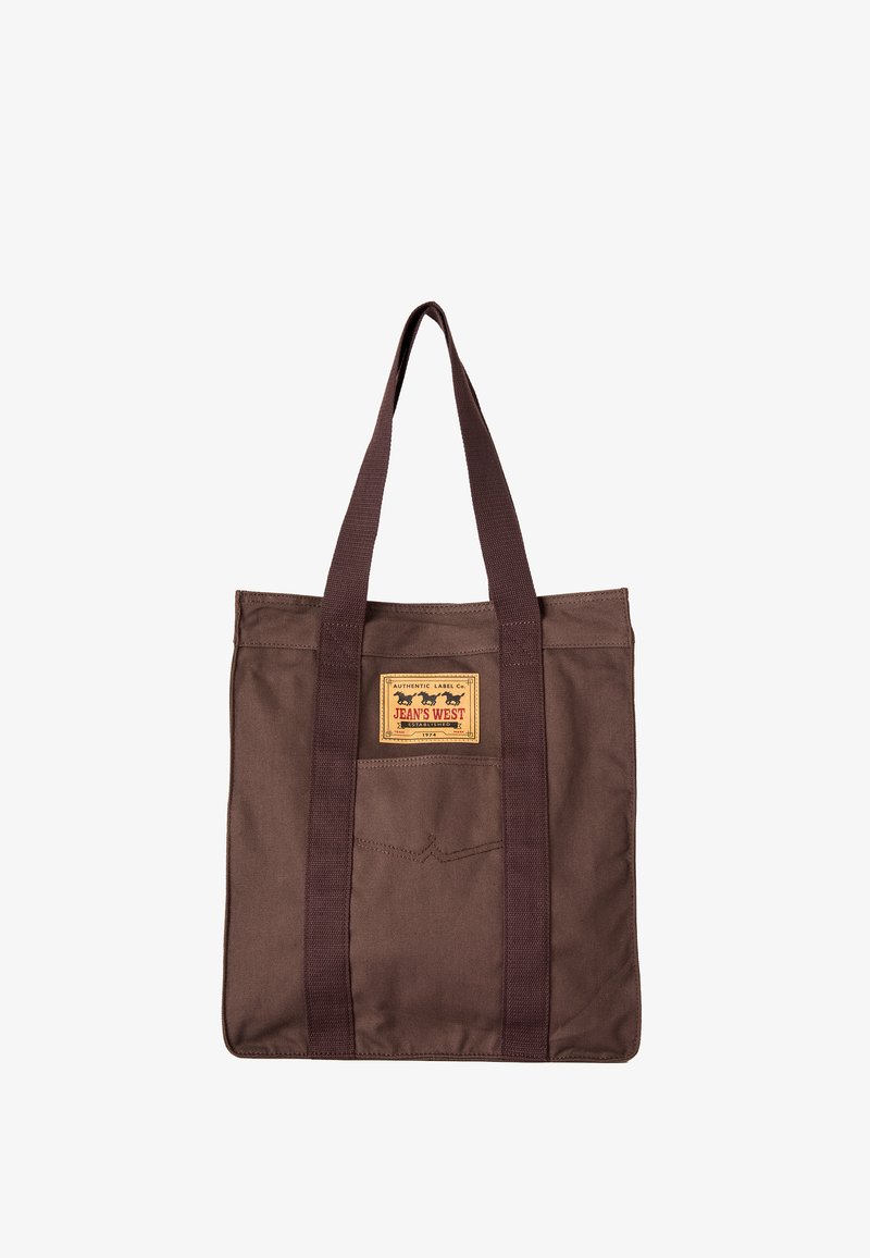 Sac fourre-tout en toile marron avec de longues poignées brun foncé et un patch rectangulaire jaune portant l'inscription « Jean's West » à l'avant.