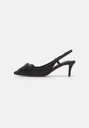 Czarny czubek szpilki typu slingback pokryty czarnymi ćwiekami z ozdobną kokardą z przodu i smukłym, średniej wysokości obcasem.