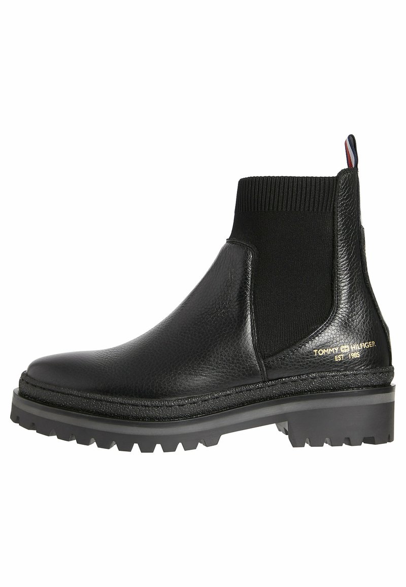Schwarze Chelsea-Stiefel aus strukturiertem Leder, mit elastischen seitlichen Einsätzen, robusten Sohlen und goldfarbenem Logo-Akzent an der Seite.