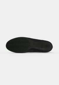 Semelle d'une chaussure noire avec un motif antidérapant texturé, nom de la marque "Gabor" embossé et un logo circulaire près du talon.