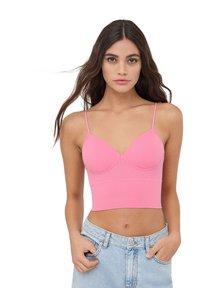 Top corto rosa a coste con spalline sottili e coppe strutturate, caratterizzato da un design aderente che esalta la vita. Indossato con jeans in denim blu chiaro.