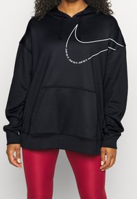 Sudadera negra de tela suave, con un gran diseño de swoosh blanco y el texto "Just do it" cerca del pecho; bolsillo tipo canguro en la parte delantera.
