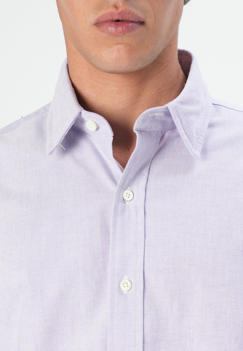 Camisa de botones lavanda hecha de tejido tejido. Presenta un cuello clásico, botones blancos y un diseño limpio y ajustado con un acabado texturizado.