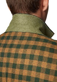 Marynarka z mieszanki wełny, z zielonym filcowym kołnierzem i brązowo-zielonym wzorem w kratę na korpusie, z widocznymi detalami ściegów.