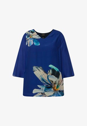 Sininen tunika, jossa on V-pääntie, vasemmassa olkapäässä isot valkoiset ja siniset kukkakuviot sekä 3/4-pituiset hihat. Suora kankaan pinta.