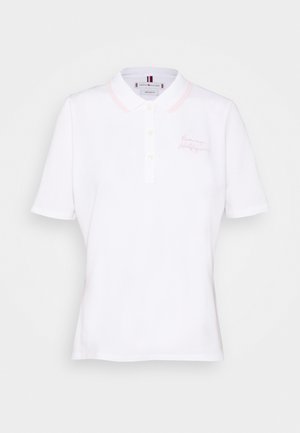 Valkoinen lyhythihainen poolopaita, jossa on kolme nappia, pehmeän vaaleanpunainen kauluksen reuna ja hienovarainen vaaleanpunainen kirjailu vasemmalla rinnalla.