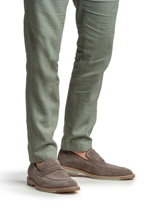 Gray suede loafers with a textured finish, featuring dual stitching and a rounded toe. Paired with light green tapered pants.