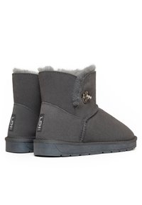 Botas de tobillo de ante gris con un suave forro de piel de oveja gris, que presentan un acento de botón lateral y una suela de goma duradera.