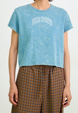 Blue, cropped cotton T-shirt with a marbled texture and "NIKE SPORTS" printed in white arched lettering on the front. Short sleeves.