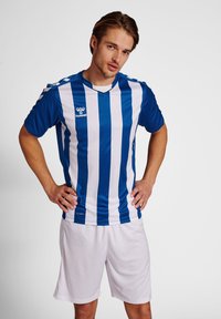 Blå och vit randig fotbollströja med korta ärmar och V-hals, parat med vita shorts. Har ett ventilerande material och logotypdetalj.