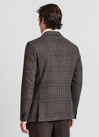 Blazer in lana a scacchi marrone con accenti blu navy. Dettagli notevoli includono un design slim, spalle strutturate e due aperture posteriori.